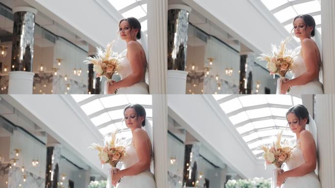 光彩照人的新娘手持花束在优雅的场地。身着婚纱的美丽新娘手持捧花。祝美丽的新娘新婚快乐。