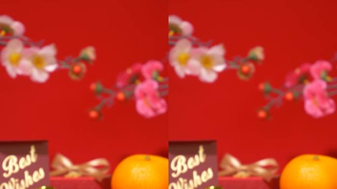 中国农历新年的红色背景环。中国古代金条装在丝绸袋子里，礼盒里有文字祝福，橘子、纸扇、梅花、蜡烛摇曳在
