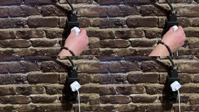 把电线插到墙上插座上的人