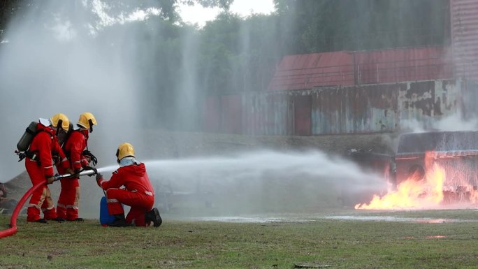 消防员的概念。消防队员用水和灭火器灭火。在一次消防训练演习中，消防员用水管和水扑灭火灾