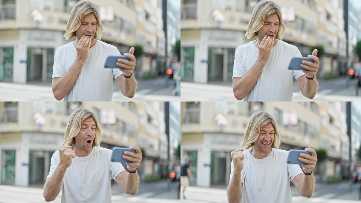 忧心忡忡的金发男子在城市街道上使用智能手机，用成功的手势转变为兴奋。