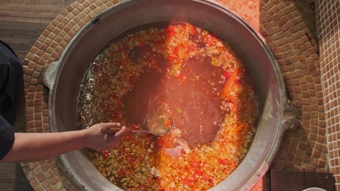 厨师用漏勺在大锅里拌肉汤和蔬菜