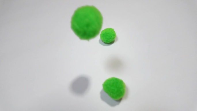 绿色的绒球落在白色的背景上。
