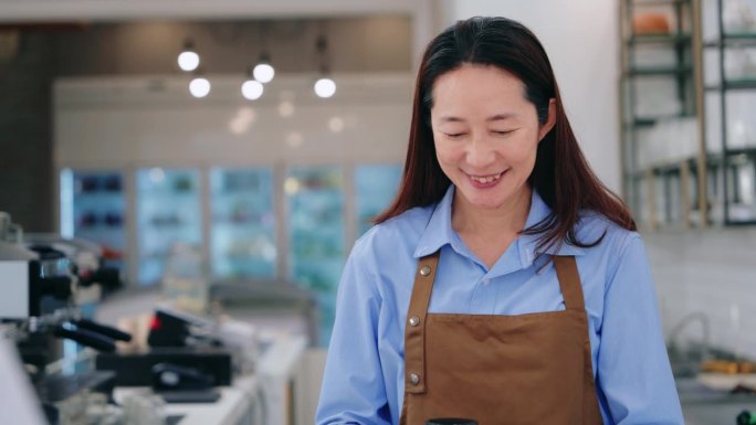 一个微笑的亚洲女服务员在咖啡店里，递给顾客一个热杯子，描绘了热情好客和优质的客户服务。