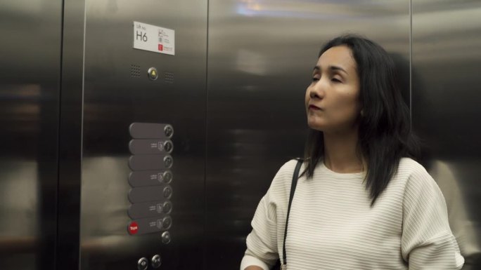 亚洲女人在停车场购物部按电梯按钮。