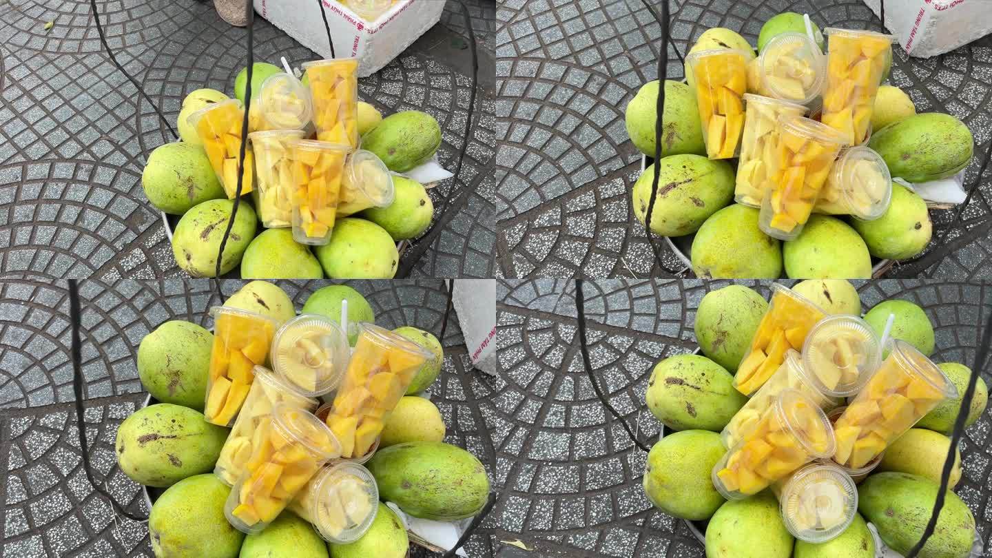 街头小贩们去买塑料袋里切成方块的芒果给马来西亚、中国、韩国、日本的游客。美味的街头小吃，尤其是新鲜的
