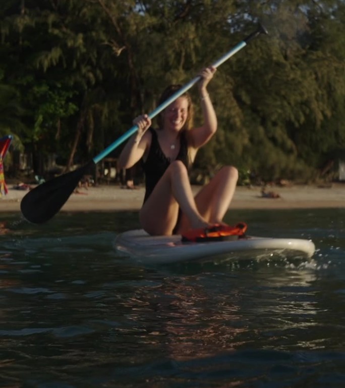 一个微笑的白人女孩在泰国的海滩上划桨冲浪