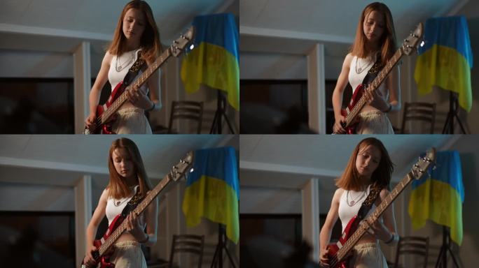 一名年轻的红发女孩站在一所音乐学校里，墙上挂着乌克兰国旗，她精力充沛地弹着贝斯吉他。