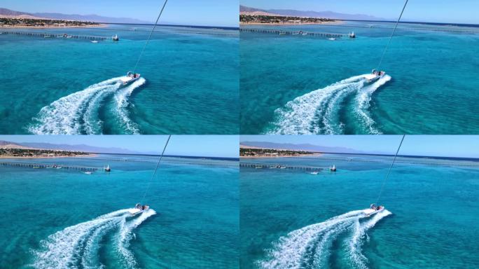 在红海蔚蓝的水面上，从滑翔伞到快艇的景色。