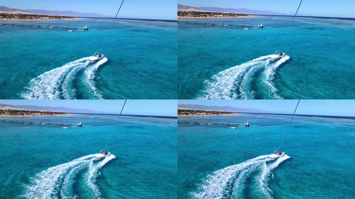 在红海蔚蓝的水面上，从滑翔伞到快艇的景色。