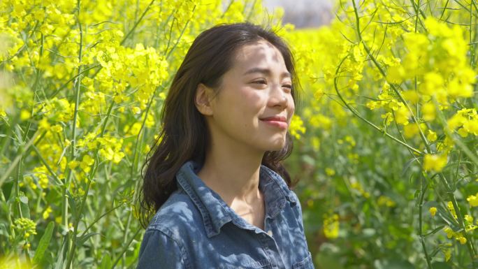 油菜花海里赏花的美女特写春天阳光温暖