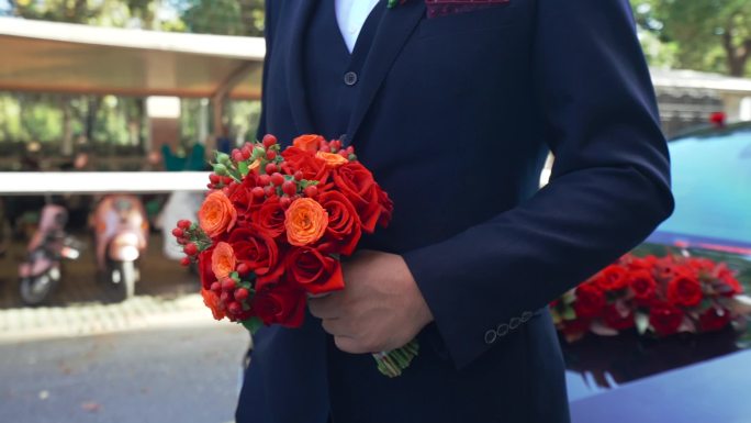 西装男人手里的鲜花手捧花红色