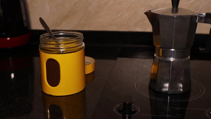 玻璃陶瓷顶部的铝制老式咖啡壶和一个黄色的咖啡粉罐子