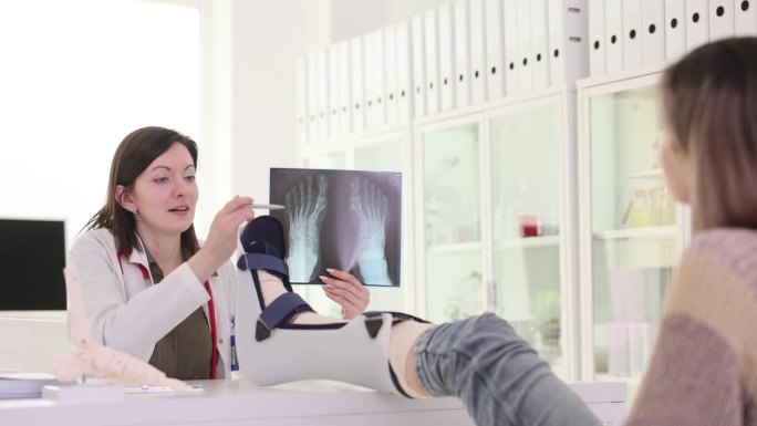 伤科医生在用绷带包扎的4k慢动作电影中向断腿病人展示脚部骨骼的x光片