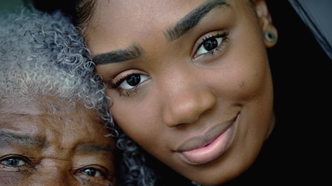 年轻的孙女和满脸皱纹的祖母的肖像，两代人的脸部特写对比。非洲裔南美拉丁人