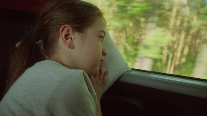 十几岁的孩子坐在车里，看着窗外的大自然，在枕头上睡着了。火车上累小孩