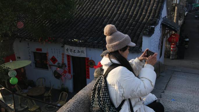 清晨年轻女子在乌镇古桥上用手机拍视频