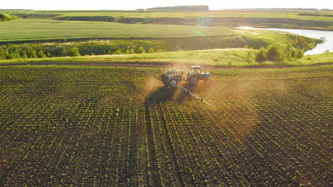 工作拖拉机在绿地上喷洒喷雾器、除草剂和农药的鸟瞰图。农业综合企业和农业。食品行业。种植植物。喷洒杀虫