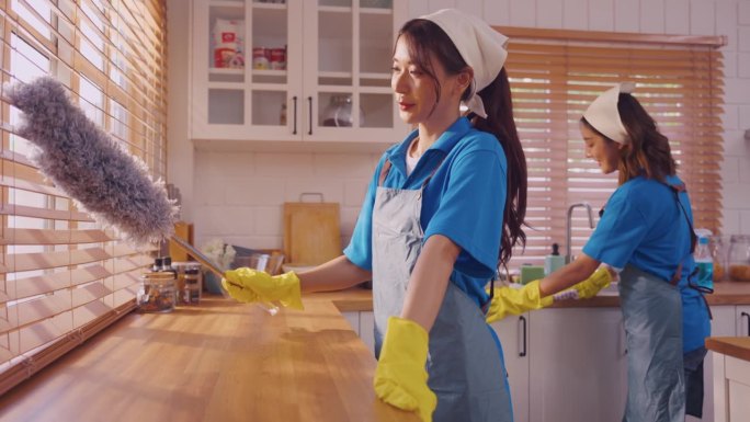 亚洲年轻女性清洁团队在家中厨房工作和清洁。美丽的管家清洁人穿着围裙和清洁肮脏的餐台为管家家务和家务在