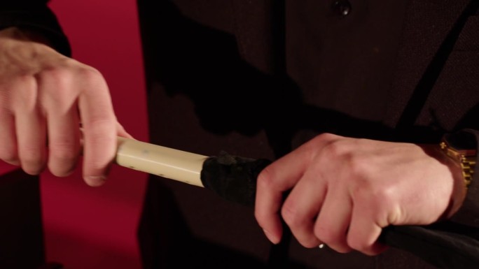 从箱子里拿出一支笛子。一个穿着黑色燕尾服的男人的手从一个红色背景的盒子里拿出一支长笛