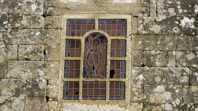 彩色玻璃窗展示了穿着寒服的流浪者，设置在石墙立面上