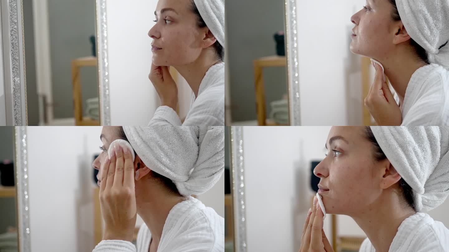 年轻的女士用镜子旁的化妆棉孜孜不倦地护理自己的皮肤，这是她的自我护理程序。