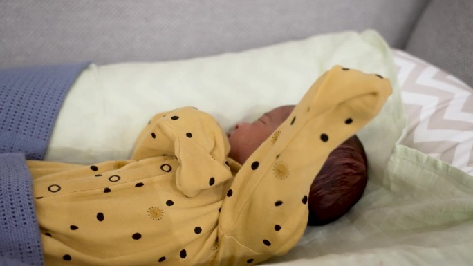 一个1周大的新生婴儿穿着黄点睡衣安静地睡觉的珍贵时刻，体现了新生儿和婴儿宁静的本质。