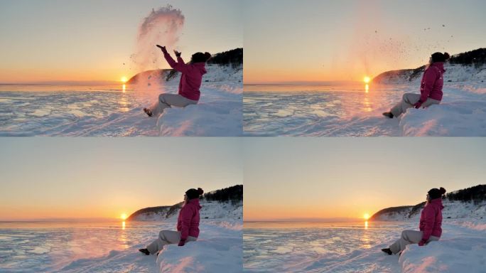 欢快的年轻女子在冰封的海面上抛起雪花，映衬着柔和的冬日夕阳。在美丽的冬季景色中玩耍