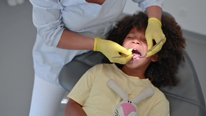 儿科牙医在牙科诊所为一个儿童病人诊治的儿科医生。