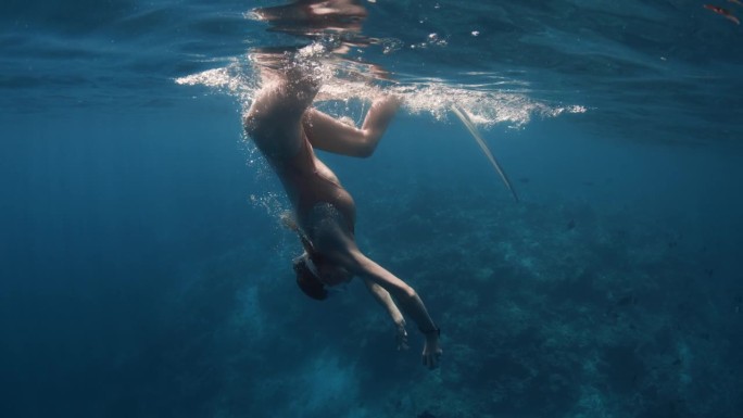 一名女自由潜水者在潜入透明的海洋深处前吸了最后一口气