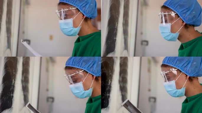 在外科手术过程中，女医生一边对比x光片，一边看着另一张x光片