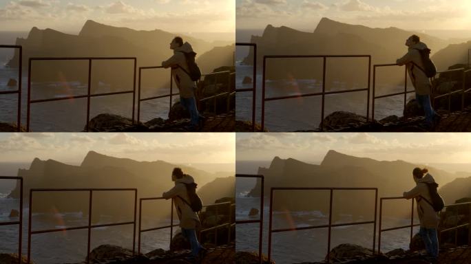 日出时站在高处眺望海洋的女人。回到马德拉岛的自然之旅。