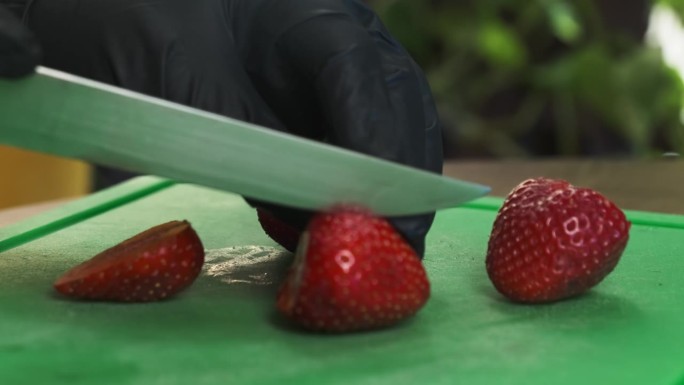糖果师戴着乳胶手套切片草莓特写