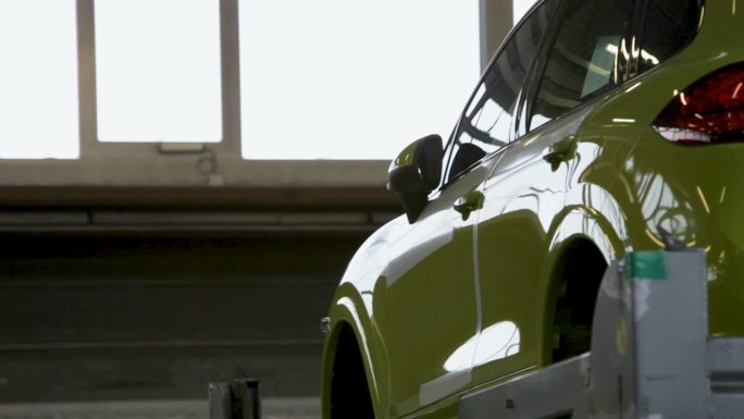 一辆石灰绿色汽车的侧视图停在明亮的车库里，光线透过窗户，部分视图