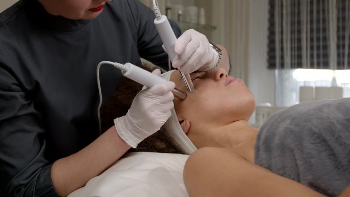 美容师用仪器给黑人妇女做微电流面部治疗