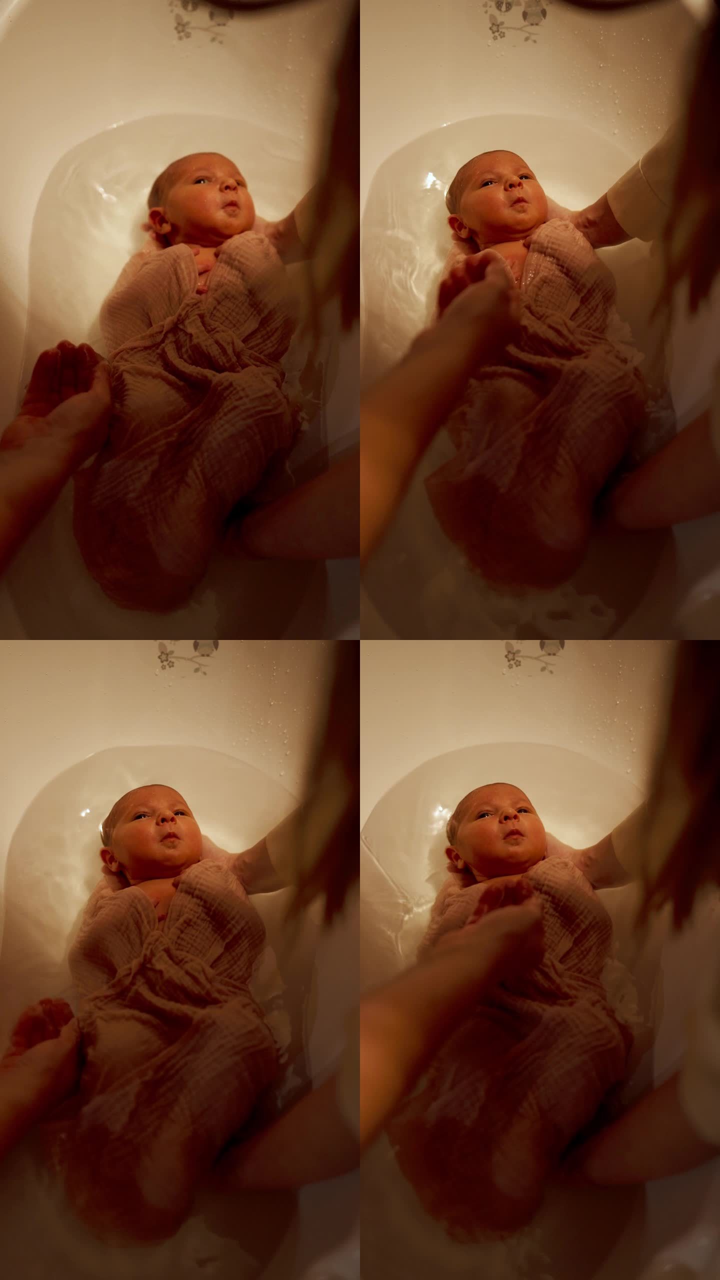 小婴儿躺在浴缸里的水里。妈妈的手在倒水。俯视图宝宝第一次洗澡。垂直视频