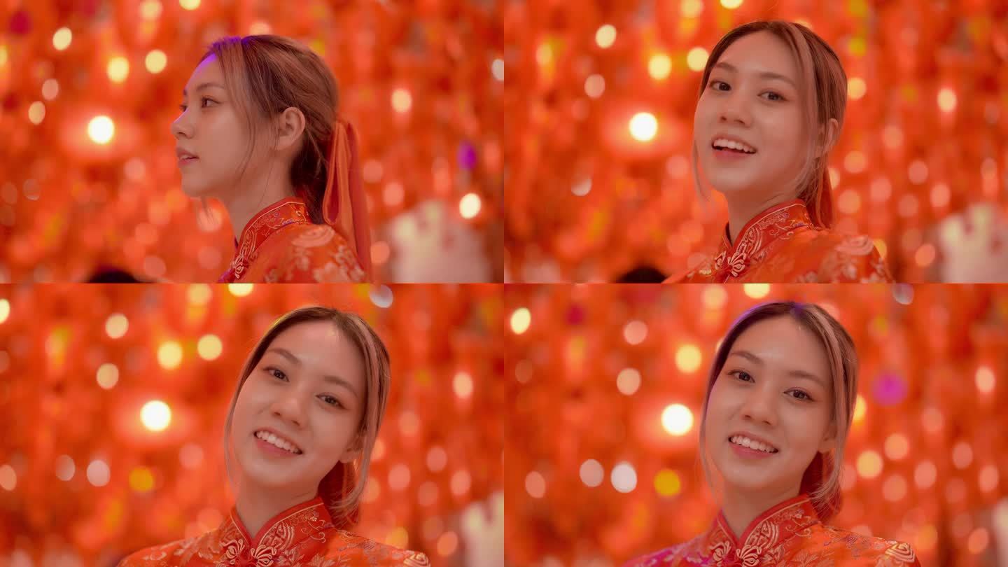 年轻的亚洲女孩在中国寺庙里穿着红色旗袍微笑的画像，寺庙里装饰着纸红灯笼。