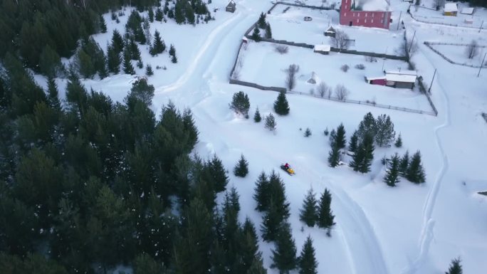 雪地摩托沿着森林道路行驶的俯视图。夹。雪地摩托骑在美丽的白雪覆盖的乡村道路上。森林地区的冬季雪地摩托