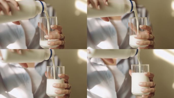 手将牛奶从瓶子倒进玻璃杯的特写镜头
