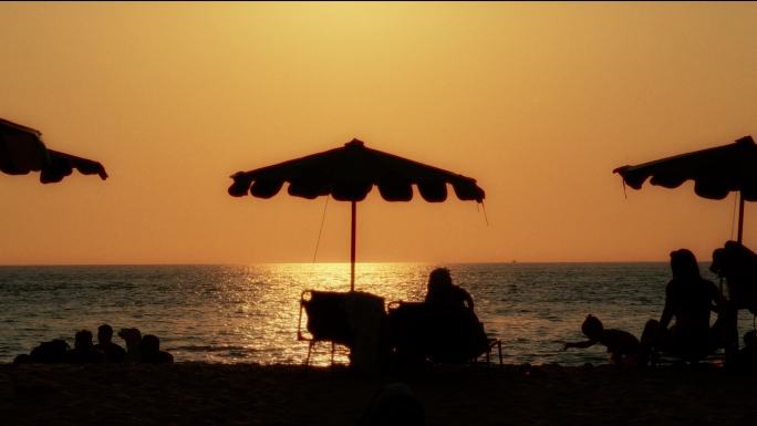 海边日落沙滩太阳伞人物休闲剪影唯美夕阳