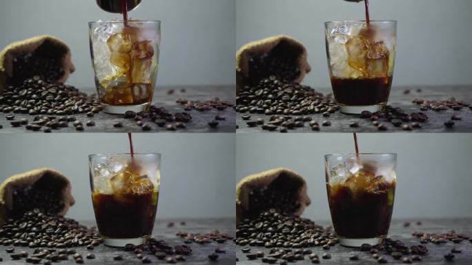 把煮好的咖啡倒在冰块上。做冰黑咖啡。加冰的冷咖啡。慢动作4k。把黑咖啡加冰倒进杯子里。美丽的烟雾。