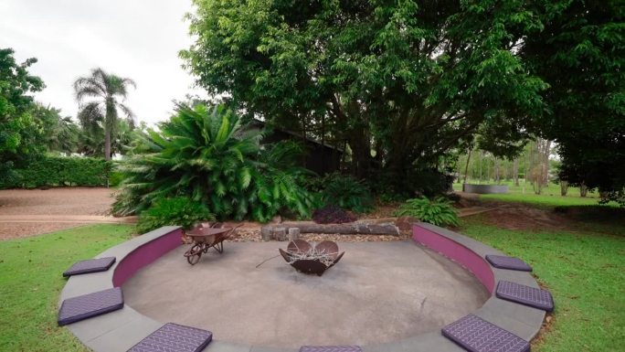 乡村著名的热带风格家庭火坑区在圆形下降的长凳与座垫，回拉。房屋外部用于不动产。