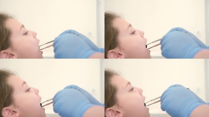 4 k的视频。一个漂亮的小女孩坐在牙医的椅子上，医生用镜子和镊子检查她的牙齿。在牙科诊所。