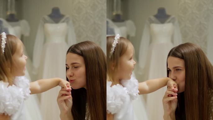在婚礼沙龙里，年轻女子和穿着白色礼服的小女孩深情地牵着手，两人都面带微笑。家庭依恋的概念