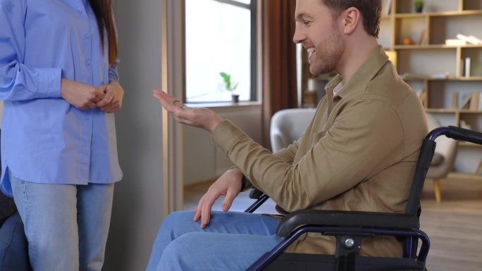 坐在轮椅上的男子将手掌向两侧伸出。一名妇女从为残疾人准备的新房里拿出钥匙和钥匙链