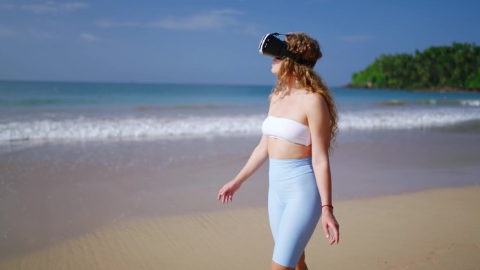 戴VR头显的女人探索虚拟海滩，在沙滩上行走，体验身临其境的海岸环境。海边休闲科技，互动游戏，未来旅游