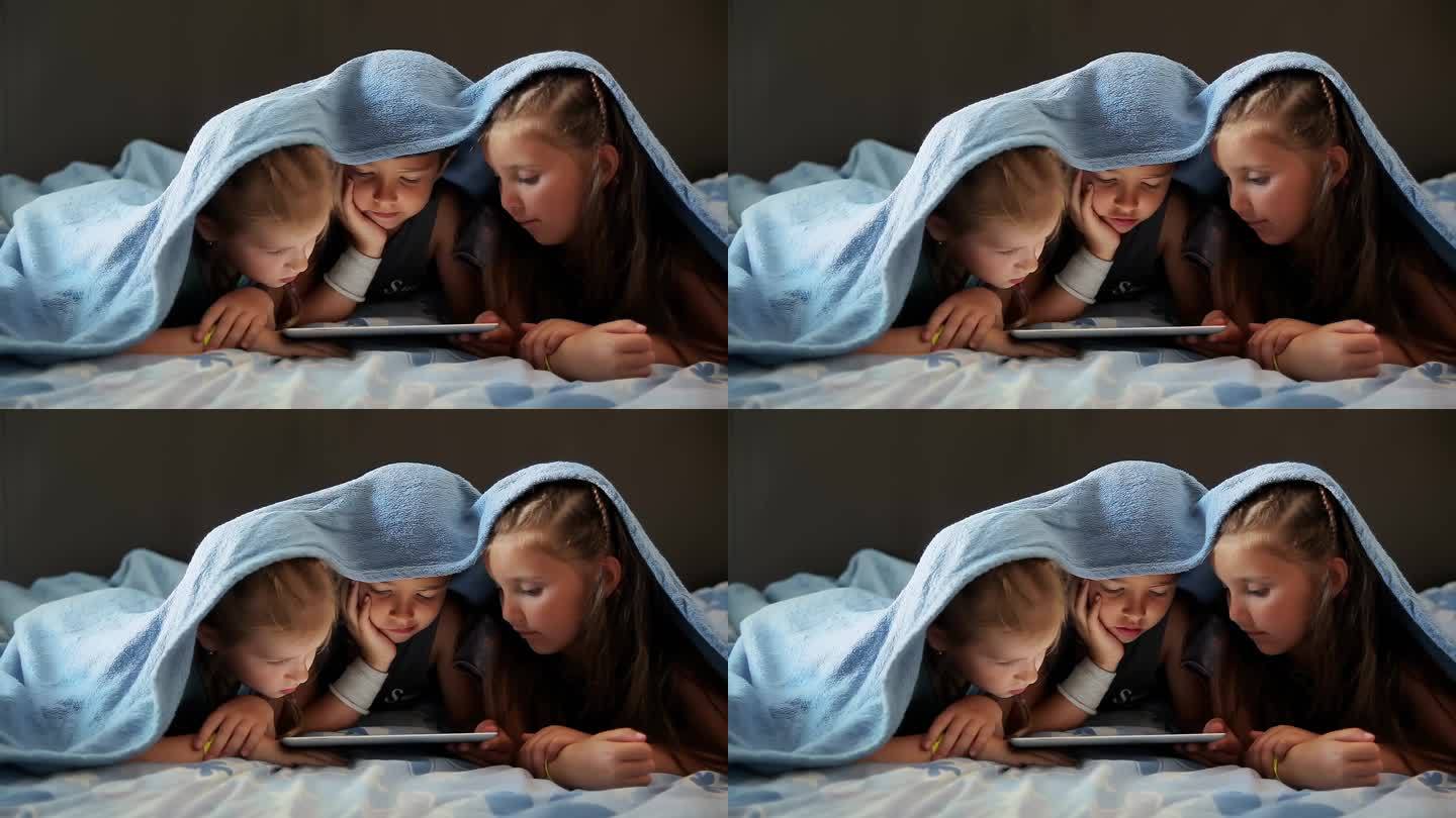 孩子们盖着毯子看着平板电脑