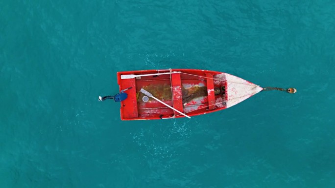 旧的红色木船，脏水系在浮标上，油漆脱落，桨留在里面，空中俯瞰