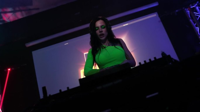 DJ在夜总会的转盘上播放迪斯科音乐。有纹身的性感女孩DJ。