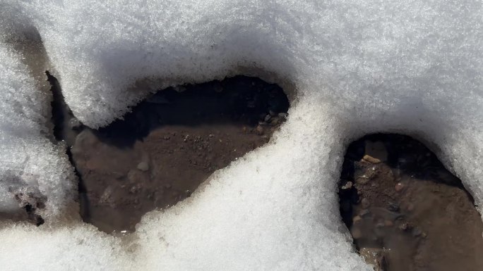 瞥见一条小溪穿过白雪覆盖的地面，暗示着从冬天到春天的过渡。